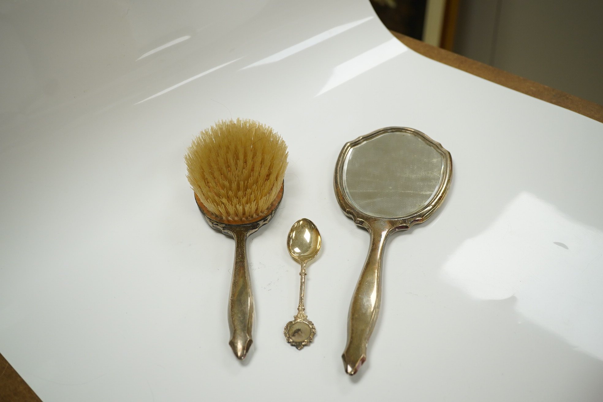 Sundry silver including a silver salver by Garrard & Co, London, 1964, two small dishes, napkin ring, pepperette, a mounted glass butter dish, spoon and a mounted hand mirror and brush, 23.3oz. Condition - poor to fair